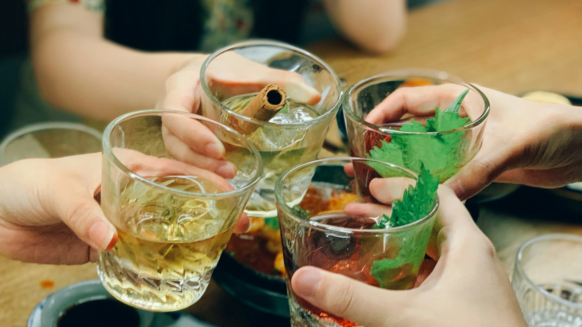 a group of hands holding glasses with liquid in them