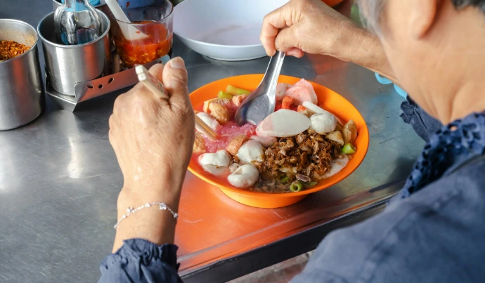 person holding stainless steel spoon and bowl with food
